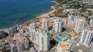 Un edificio residencial alto con varios balcones, una piscina y vista al mar.