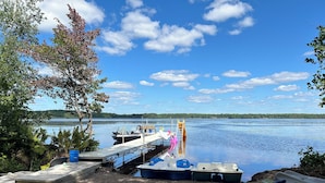 Ein Steg am See mit Booten, Stühlen und einer Leiter.