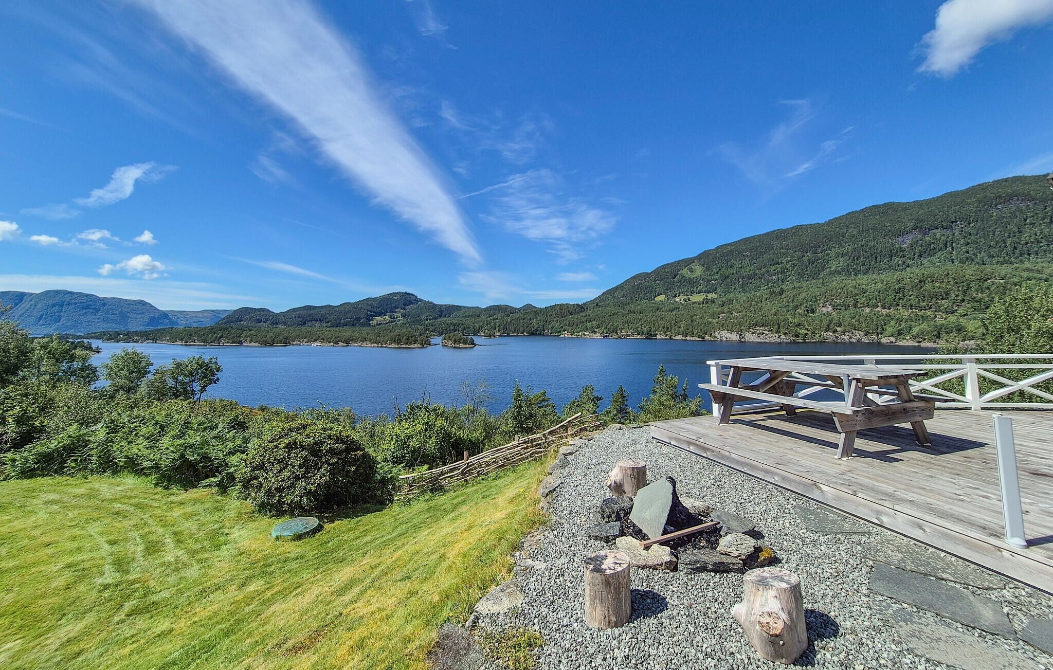 Een terras aan het meer met een picknicktafel en uitzicht op een meer en bergen.