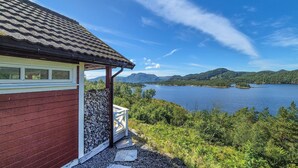 Une cabane avec un mur en pierre et une vue sur un lac et des montagnes.