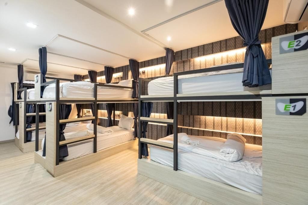 A dormitory-style room with bunk beds, each labeled with an 'E' number.