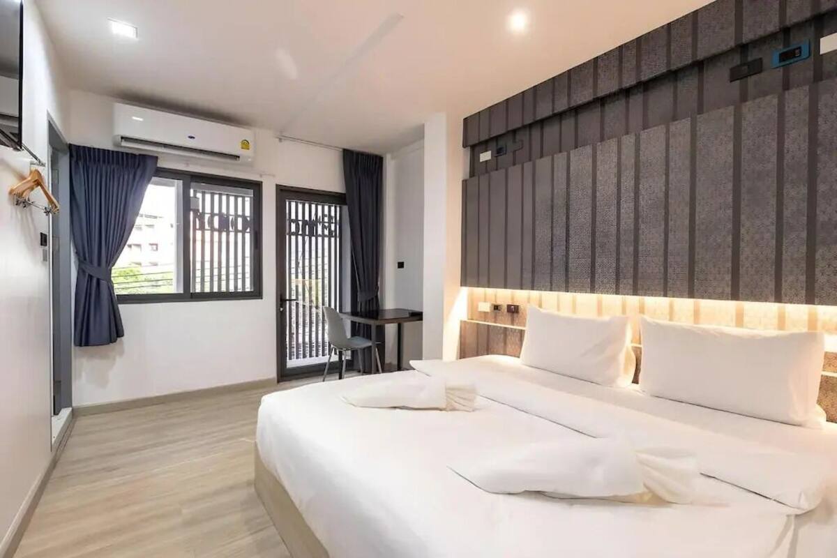Une chambre d’hôtel moderne dotée d’un grand lit, d’un bureau et offrant une vue sur l’extérieur grâce à une fenêtre donnant sur un balcon.