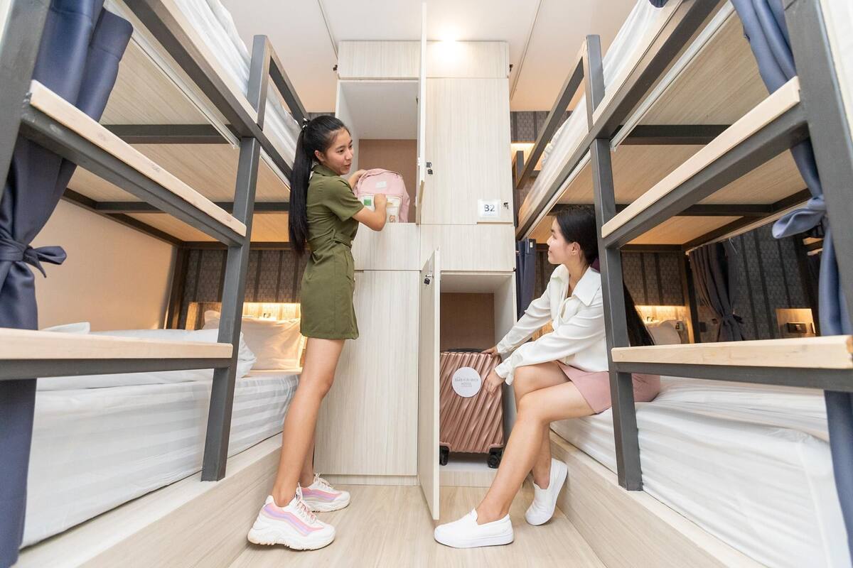 Une chambre avec un lit superposé, une valise et un sac à dos posés sur le lit.