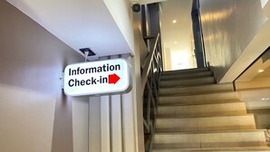 A staircase with a sign indicating an information check-in area to the right. - Baan Kun Mhor Hostel (Bangkok)