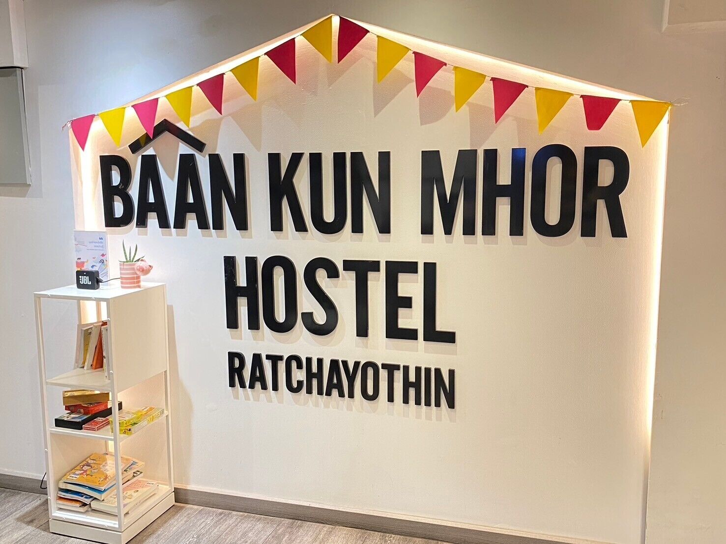 A hostel sign with the name 'BAAN KUN MHOR HOSTEL' and 'RATCHAYOTHIN' written on it.