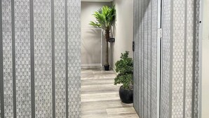 A hallway with patterned wallpaper, a palm plant, and a potted shrub. - Baan Kun Mhor Hostel (Bangkok)