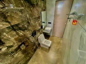 A bathroom with a marble floor, a white toilet, a sink, and a shower area.