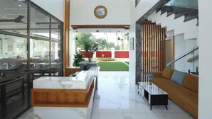 A modern interior with a kitchen area, a seating area with a sofa and coffee table, and a staircase. - Sandhya Manohar Beach Resort (Alibag)