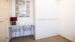 Une salle de bain moderne avec un meuble-lavabo blanc, un miroir doté d’un cadre texturé et une armoire blanche.