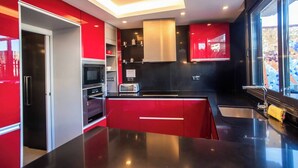 Une cuisine moderne avec des meubles de rangement rouges, un plan de travail noir et des appareils électroménagers en acier inoxydable.