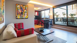 Un salon moderne avec un canapé, une table basse et un tableau abstrait aux couleurs vives.