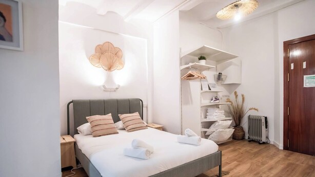 A modern bedroom with a bed, bedside tables, a wardrobe, and a radiator.
