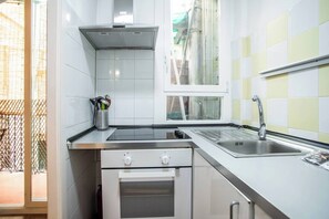 A compact kitchen with a built-in oven, a stainless steel sink, and a window overlooking the street. - 44POC1062 - Studio newly decorated in Poble Sec (Barcelona)