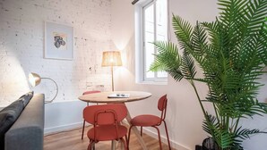 A cozy room with a round wooden table, red chairs, a lamp, and a large green plant.