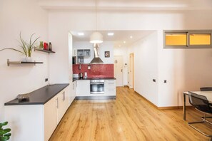 Cozinha moderna com piso de madeira, uma ilha central e um espaço de refeições com uma cadeira.