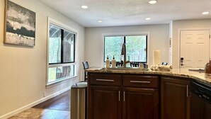 A kitchen with a large island, wooden cabinets, and a window providing a view of trees. - Whispering Pines: Garage Parking & Game Room (Pollock Pines)