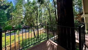 A balcony with a view of a forested area and a road. - Whispering Pines: Garage Parking & Game Room (Pollock Pines)