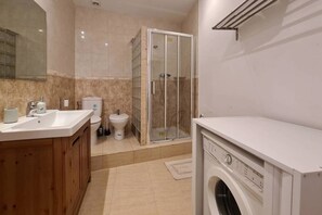 A modern bathroom with a sink, toilet, shower, and washing machine. - 21ara1085- 4br apartment in Gótico (Barcelona)