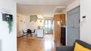 A compact living space with a dining area, kitchenette, and a grey door with a phone. - 32ara1086 - 3 bedrooms apartment (Barcelona)