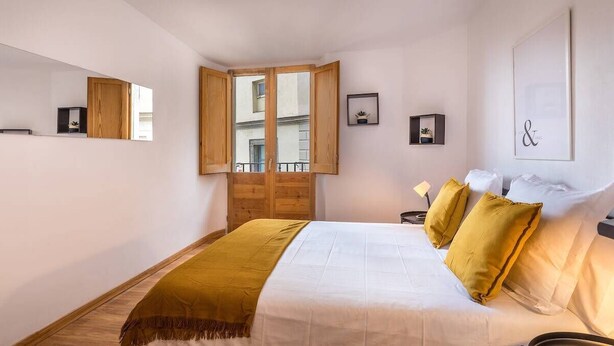 A bedroom with a bed, a wooden wardrobe, a window, and a wall-mounted shelf. - 32ara1086 - 3 bedrooms apartment (Barcelona)