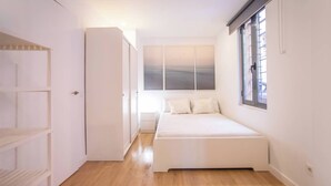 A small, bright bedroom with a bed, a window, and a painting on the wall. - BPAR1088 - Cozy flat near the beach (Barcelona)