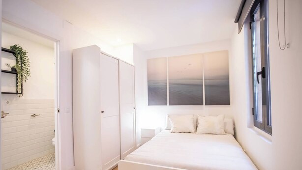 A bedroom with a bed, a wardrobe, a window, and a wall-mounted artwork. - BPAR1088 - Cozy flat near the beach (Barcelona)