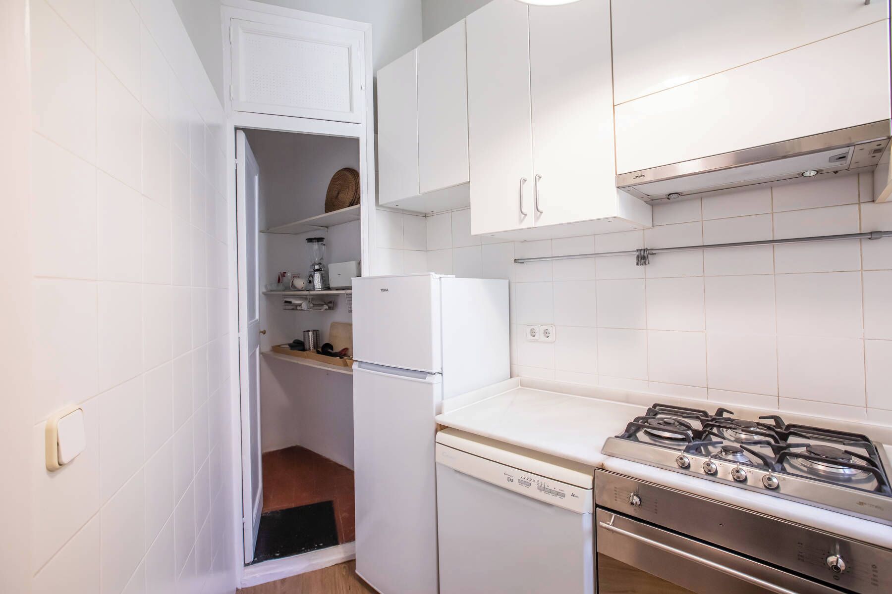A compact kitchen with white cabinets, a white refrigerator, a dishwasher, and a gas stove.