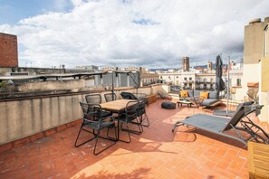 Une terrasse sur le toit, avec une table et des chaises en bois, un canapé et un espace détente.