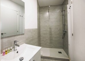 Une salle de bain moderne avec une douche, un lavabo et un miroir.