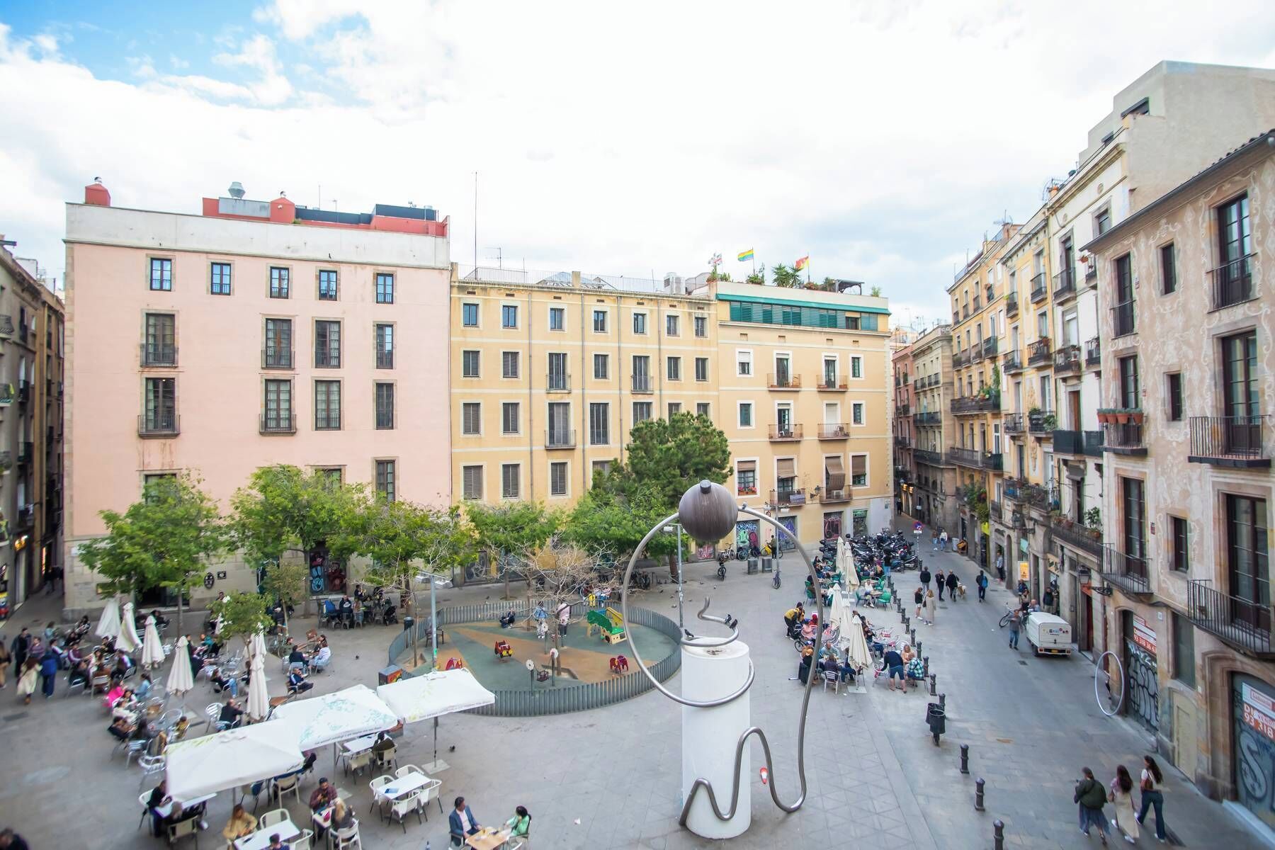 A public square with outdoor seating, surrounded by multi-story buildings with balconies.