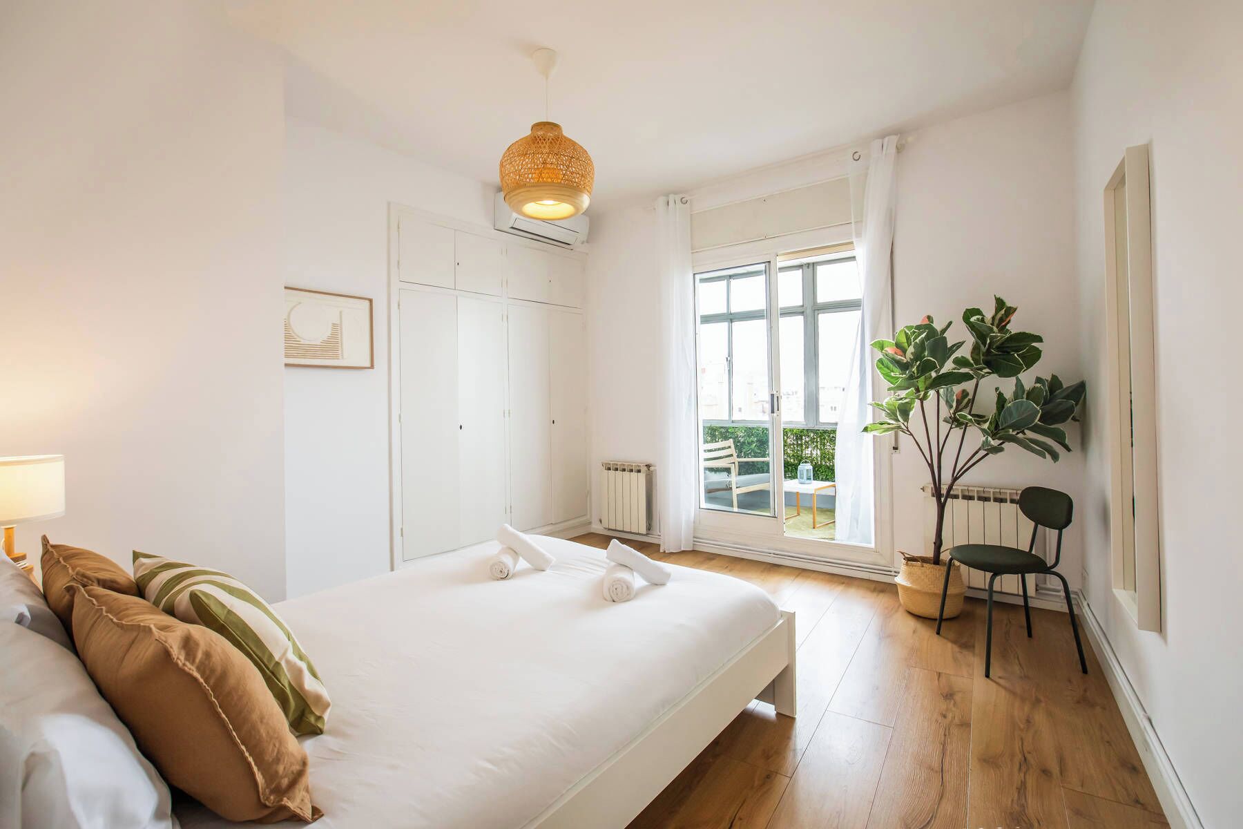 A bedroom with a bed, a radiator, a window with curtains, a plant, and a chair.
