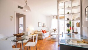 Ein modernes Wohnzimmer mit einem Glastisch, weißen Sofas und einem Bücherregal.