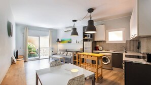 A compact living space with a dining area, kitchen, and a balcony with outdoor furniture.
