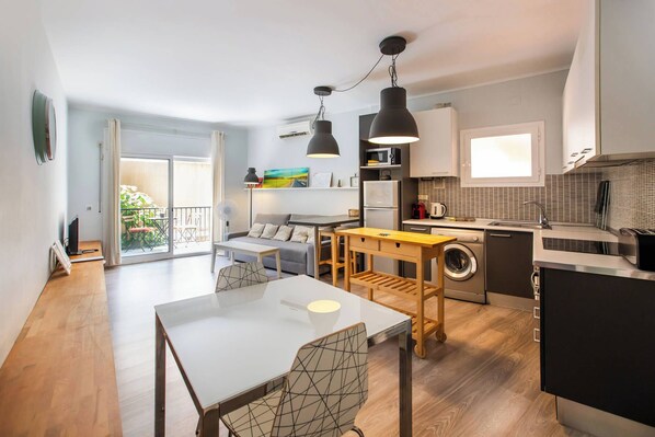 A compact living space with a dining area, kitchen, and a balcony with outdoor furniture.