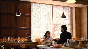 Un restaurante con paneles de madera, ventanas grandes con diseño de ladrillo e iluminación colgante.