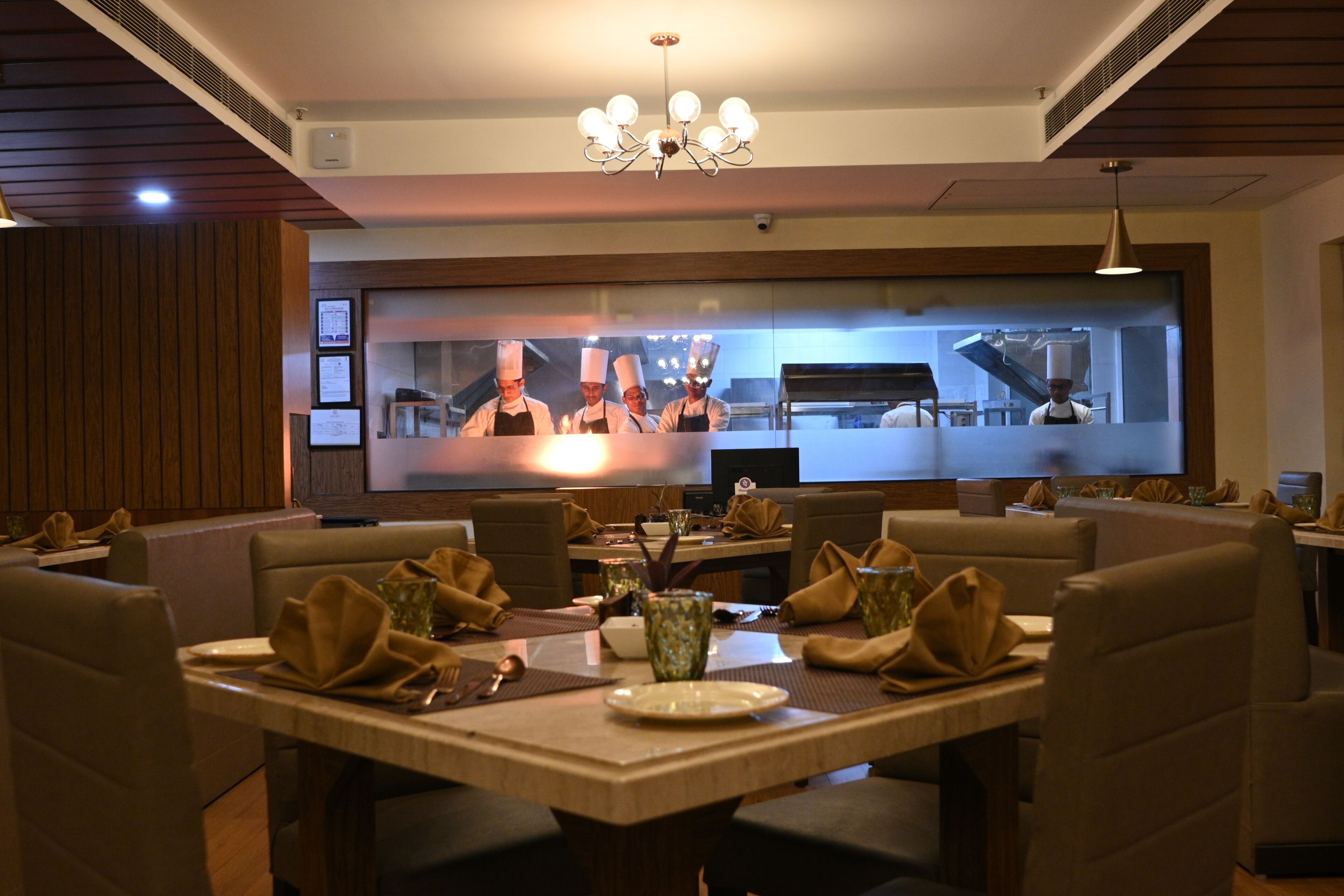 A restaurant with booths and a central dining area. There are chefs visible in the background.
