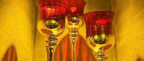 Tres copas de vino con tallos rojos y base transparente, colocadas dentro de un recipiente metálico reflectante.