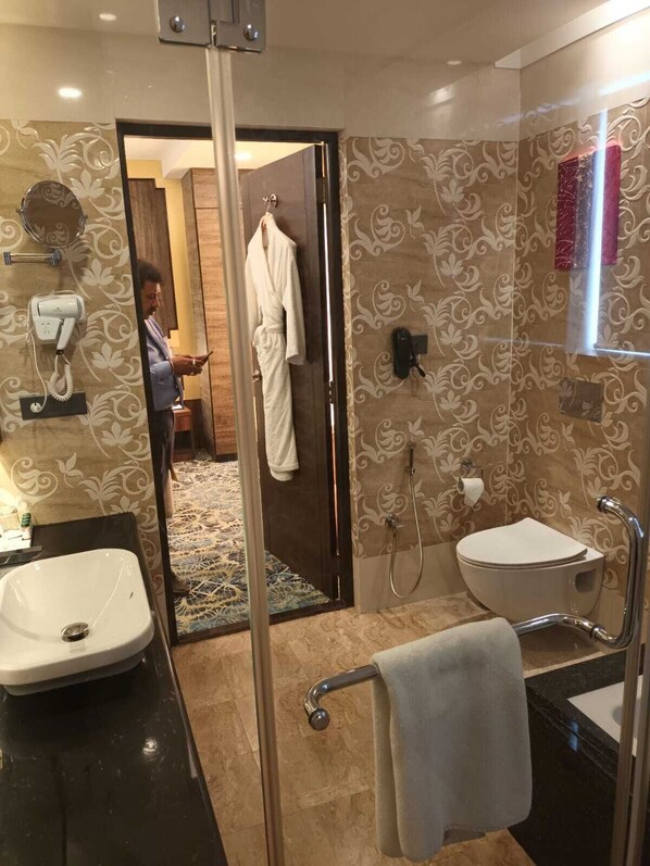 A modern bathroom with a glass shower enclosure, a white sink, a toilet, and a vanity with a mirror.