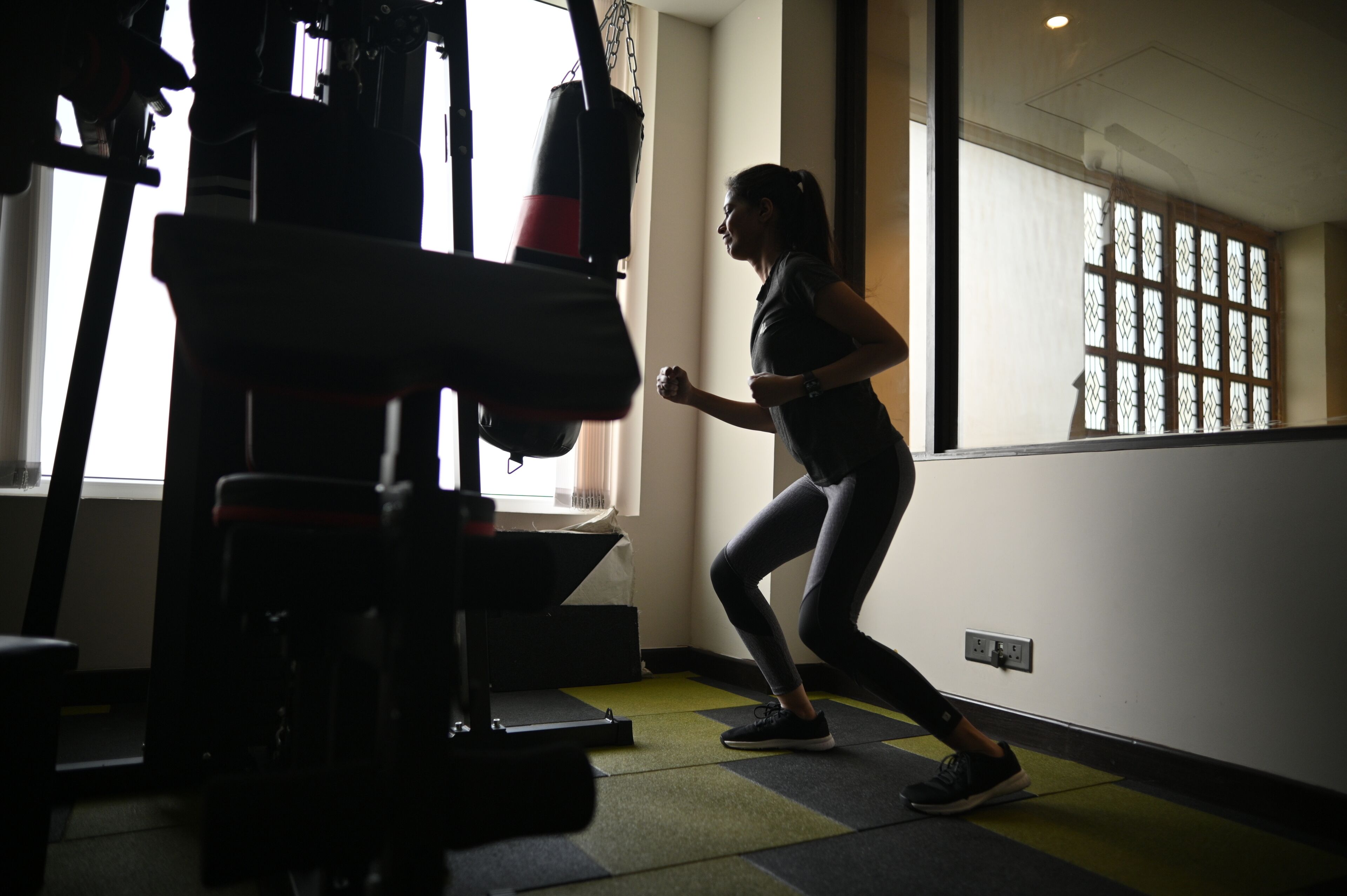 A person running in a gym with exercise equipment and a window with a view.