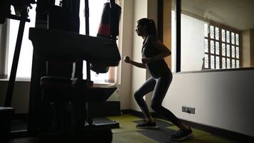 A person running in a gym with exercise equipment and a window with a view.