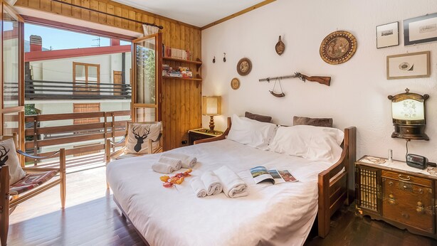 Ein Hotelzimmer mit einem Bett, Holzmöbeln, einem Fenster und Wanddekorationen.
