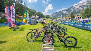 Ein Mountainbike-Event mit mehreren Fahrrädern, die auf einer Wiese geparkt sind, umgeben von Zelten und Flaggen.