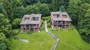 A cluster of two-story buildings with a central staircase connecting them, surrounded by dense forest. - Il Vecchio Faggio: Lake Maggiore View Terrace (Gignese)