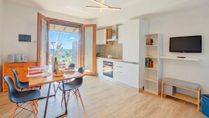 A modern kitchen with a dining area, a TV, and a balcony with a view. - Il Vecchio Faggio: Lake Maggiore View Terrace (Gignese)