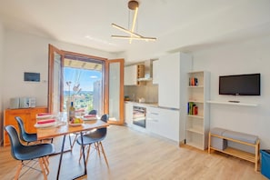 Et moderne køkken med spiseplads, et fjernsyn og en balkon med udsigt.