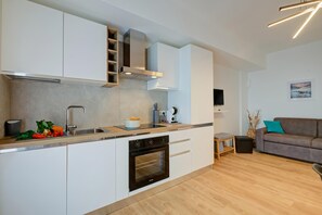 A modern kitchen with white cabinetry, a built-in oven, and a wooden countertop. - Il Vecchio Faggio: Lake Maggiore View Terrace (Gignese)