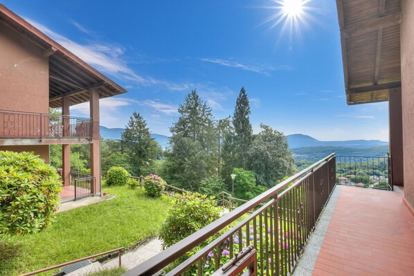 Un balcon donnant sur un jardin luxuriant et sur des montagnes lointaines.