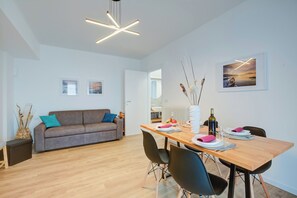 A modern living room with a sofa, dining table, and chairs. - Il Vecchio Faggio (Gignese)