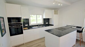 Une cuisine moderne avec des meubles blancs, un plan de travail noir et un four encastré.
