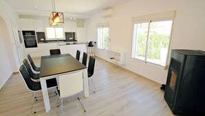 Une cuisine moderne avec des meubles blancs, un coin repas comprenant une table et des chaises, et une grande fenêtre laissant entrer la lumière naturelle.